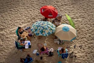 A group of women playing bingo while sitting under an umbrella and protecting themselves from the sun on Cadiz Beach