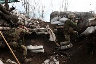 Soldados ucranianos disparan con rifles de asalto en una trinchera en la línea del frente con tropas rusas en Lugansk