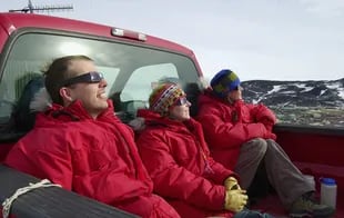 Los participantes del Programa Antártico de EE. UU. Joe Harrigan, Katie Burke y Allisha Ochs observan el eclipse solar sobre la estación McMurdo el 24 de noviembre de 2003