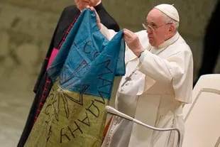 El Papa Francisco muestra una bandera que le fue traída desde Bucha, Ucrania, durante su audiencia general semanal en el Aula Pablo VI, en el Vaticano, el miércoles 6 de abril de 2022