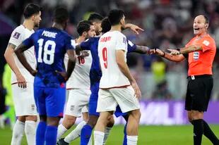 Spain's referee Antonio Mateu Lahoz talks to players during the World Cup group B soccer match between Iran and the United States at the Al Thumama Stadium in Doha, Qatar, Tuesday, Nov. 29, 2022. (AP Photo/Manu Fernandez)