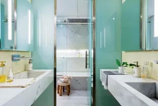 El baño de la suite tiene mesadas y revestimiento de mármol (Oscar Revestimientos), grifería cromada (Hansgrohe) y mampara de vidrio (Centro Cristales).