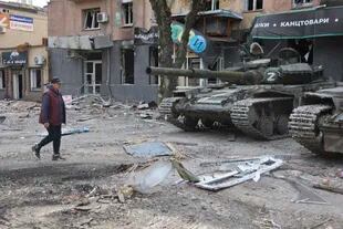 Una mujer camina frente a tanques de las fuerzas separatistas prorrusas en Mariupol, que controlan la ciudad