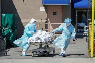Enfermeros trasladan un cuerpo a un camión refrigerador utilizado como morgue temporaria en el Hospital Wyckoff, en Nueva York