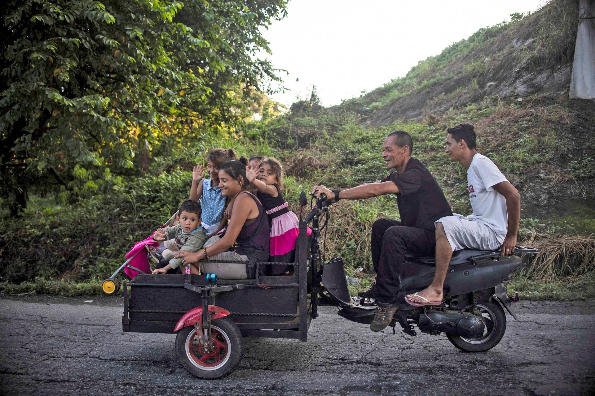 Los migrantes hondureños que se dirigen en una caravana a los EE. UU. Viajan en un carro de motocicleta improvisado en Huixtla de camino al estado de Mapastepec Chiapas, México