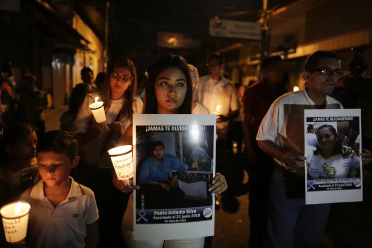 Manifestantes sostienen fotografías de familiares muertos y presos bajo el régimen de Ortega que ha dejado más de 325 muertos, 800 en prisión y miles en el exilio.
AFP