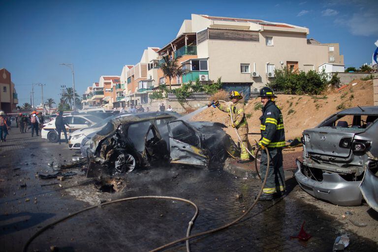 Israel, Ashkelon. Bomberos israelíes apagan el incendio de un vehículo destruido causado por un cohete disparado desde la Franja de Gaza hacia Israel, en medio de la escalada de violencia israelí-palestina 