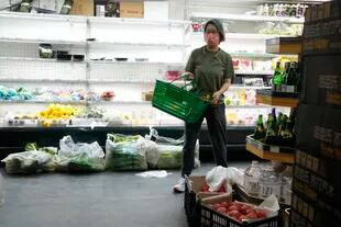Una mujer con una máscara pasa por delante de estantes medio vacíos en un supermercado en el distrito de Chaoyang el lunes 25 de abril de 2022, en Pekín. 