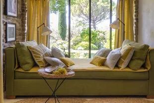 Perfectamente adaptado a la ventana que se proyecta, el sofá es una maravilla para recostarse a leer o descansar con vista al jardín.