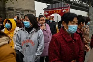 Turistas nacionales de la provincia de Henan con máscaras faciales visitan un área junto al río Yangtze en Wuhan