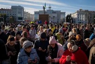 Residentes se reúnen cerca de un punto de señal de internet, el lunes 14 de noviembre de 2022, en Jersón, en el sur de Ucrania. (AP Foto/Bernat Armangue)