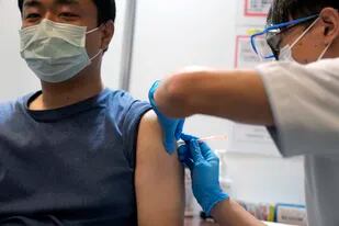 Un residente en Tokio recibe una dosis de refuerzo de la vacuna de Moderna contra el COVID-19, en un centro de vacunación masiva gestionado por la Fuerza Japonesa de Autodefensa, el lunes 31 de enero de 2022 en Tokio. (AP Photo/Eugene Hoshiko, Pool)