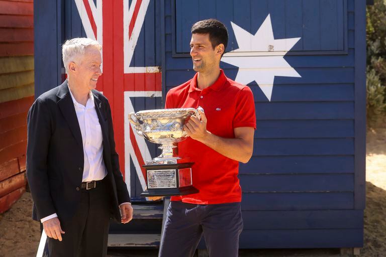 El tenista serbio Novak Djokovic, a la derecha, junto al director del Abierto de Australia, Craig Tiley en una sesión de fotos con el trofeo tras sus victoria en el torneo en Melbourne, Australia, el lunes 22 de febrero de 2021. (AP Foto/Hamish Blair)