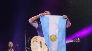 Chris Martin sostiene la bandera argentina, en uno de los shows que brindó esta semana, en La Plata