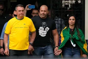 El presidente brasileño Jair Bolsonaro, a la izquierda, que se postula para otro mandato, sale de un centro de votación después de votar durante las elecciones generales en Río de Janeiro, Brasil, el domingo 2 de octubre de 2022