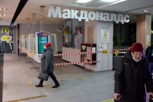 En esta foto de archivo tomada el 16 de marzo de 2022, la gente camina junto a un restaurante McDonald's cerrado en un centro comercial en Moscú. 