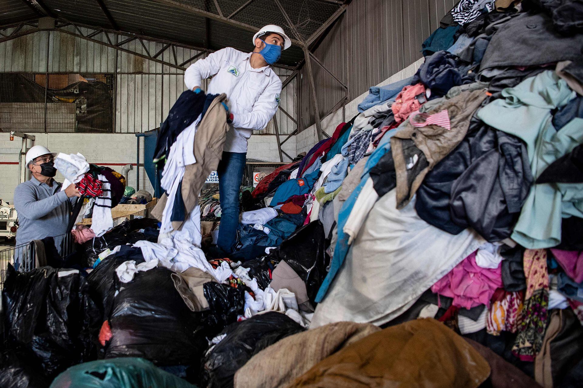 Hombres trabajan en una fábrica que recicla ropa usada desechada en el desierto de Atacama para paneles de aislamiento de madera para los muros de viviendas sociales
