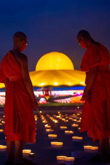 Monjes budistas encienden velas en el suelo del templo budista Wat Dhammakaya, para conmemorar la festividad budista Visakha Bucha, también conocida como el Día de Vesak
