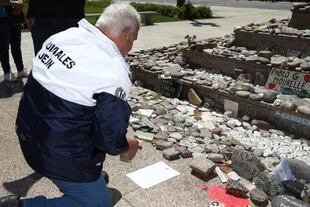 Familiares acomodan las piedras en el monumento a la muertos por covid que fue vandalizado ayer durante el acto del "Día de la Lealtad"