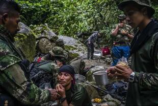 Un grupo de guerrilleros rebeldes de las FARC desayunan cerca de un arroyo.