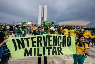 Seguidores del ex Presidente Jair Bolsonaro sostienen un cartel que dice "Intervención Civil y Militar!".