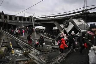 La gente cruza un puente destruido desde Irpin a Kiev (Photo by Aris Messinis / AFP)