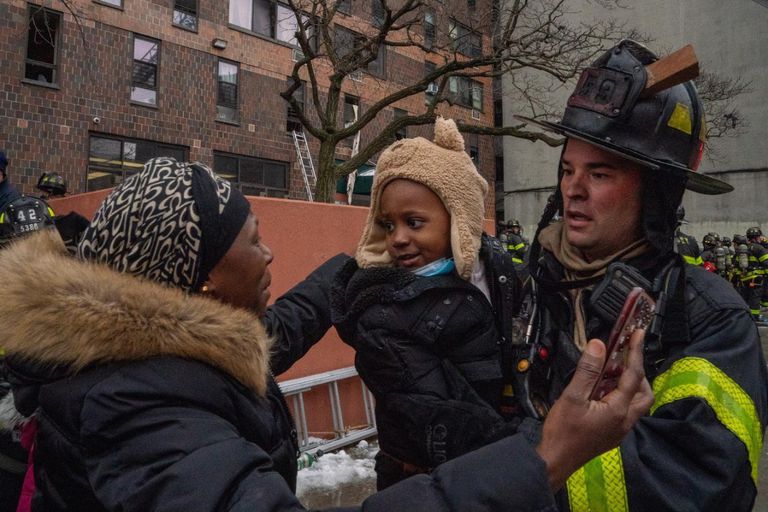 Un rescatista con un chico en brazos en las inmediaciones del edificio incendiado