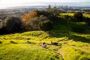 Un padre y su hijo disfrutan sobre el pasto en una colina de Auckland, la ciudad más grande Nueva Zelanda