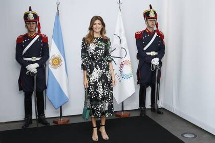 La primera dama argentina usó un vestido estampado con flores y hojas, largo midi, ceñido a la cintura. Completó su outfit con una cartera caja verde y sandalias con pulsera y tira transparente, muy de moda.