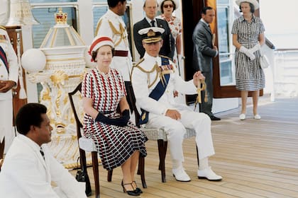 La reina Isabel II (con tacos, guantes y casquete) y el príncipe Felipe con uniforme de gala a bordo del barco durante una gira oficial por Fiji, en febrero de 1977.