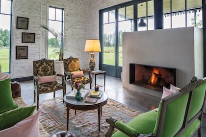 De grandes proporciones, como el espacio que la contiene, la chimenea es protagonista en la gran sala de estar y está acompañada por un juego de sillones franceses, un Chester y antiguas mesas de sala, con tapas de mármol, de estilo inglés.