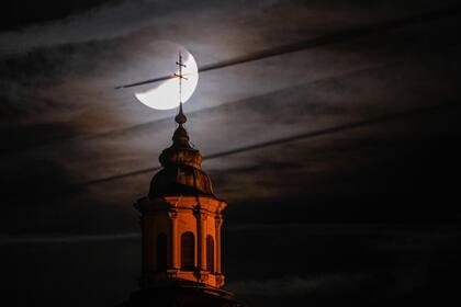 La torre de la iglesia basílica se ve frente a la luna durante el eclipse en Weingarten, Alemania