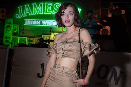 Belén Chavanne eligió un conjunto con un crop top strapless y falda en color nude, que combinó con unos aros fosforescentes de acrílico para ir a un evento de Jameson