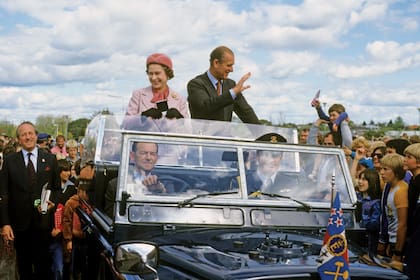 La Reina y el duque de Edimburgo saludan desde un auto durante una visita a Nueva Zelanda, donde también fueron blanco de un atentado