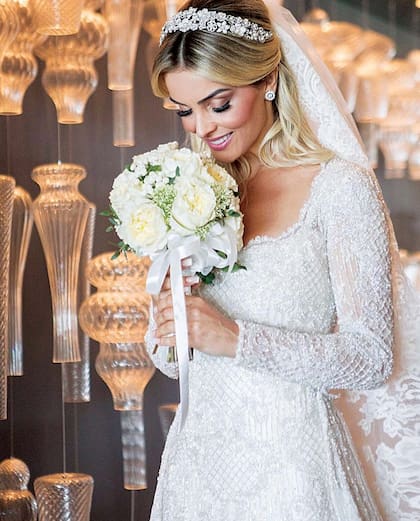 La novia lució un vestido confeccionado por la diseñadora paulista Camila Feres, bordado íntegramente con piedras y cristales, con un gran velo de encaje y una tiara de fantasía.