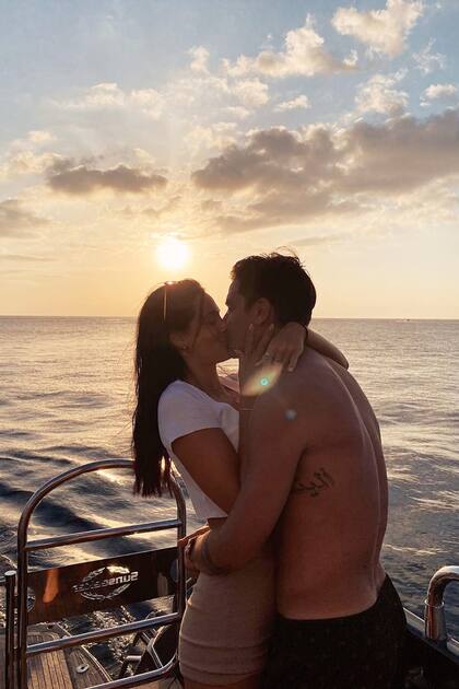 Una imagen besando a su novio con la puesta del sol detrás