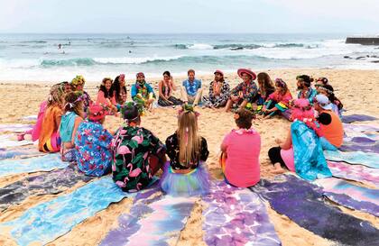 Los duques de Sussex se unieron al abrazo grupal del “Fluro Friday”. “Fluro” se refiere a fluorescente y tiene que ver con las camisas de colores brillantes y collares que usan los miembros del grupo de surf One Wave, que hacen este evento “sanador” semanalmente.