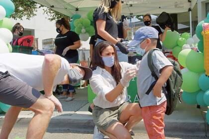 Con looks casuales y protegidos por barbijos y guantes, Harry y Meghan sorprendieron a la gente mientras les entregaban a través de las ventanas de sus autos, comida, ropa y artículos de higiene. Además, ayudaron a los más chiquitos a elegir la mochila perfecta para volver al colegio.