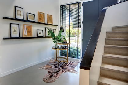 En el hall de entrada, dos mesas recibidoras en la que descansan velas aromáticas se posan sobre una alfombra de cebra traída de Sudáfrica.