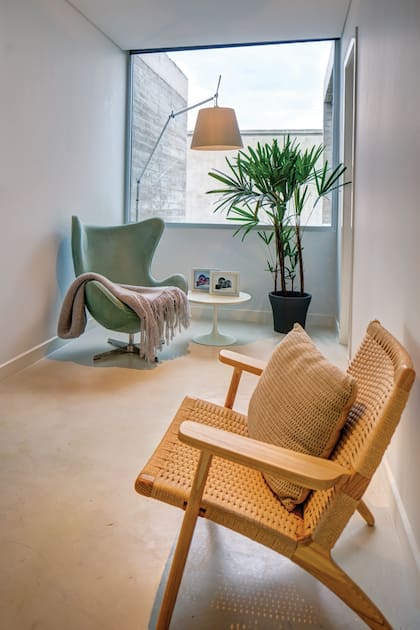 La escalera desemboca en un estar con una silla de mimbre, un sillón modelo Egg Chair y una lámpara modelo Tolomeo, de Fauna Design