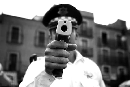 Agente con un escáner térmico para medir la temperatura. Las armas de nuestro tiempo.Por @florc_84