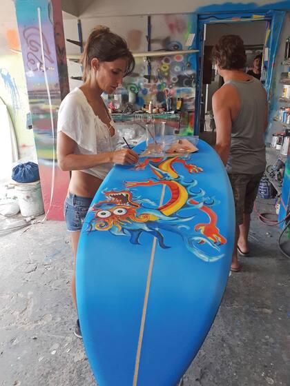 Pincel en mano, María está concentrada en la intervención de su tabla de surf.
