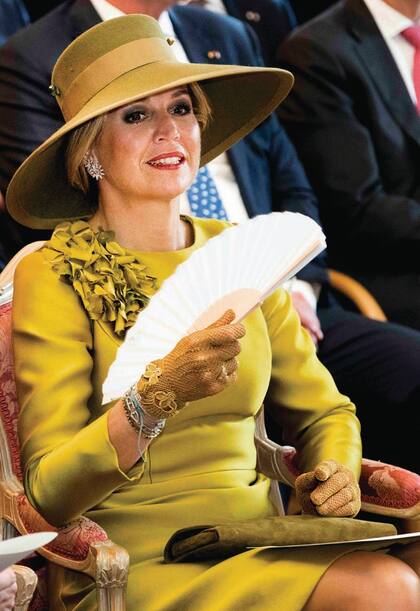 El toque dcontract del estilismo de la reina de Holanda estuvo dado por el aplique de flores en el hombro derecho. Junto con el sombrero de Delvigne, los guantes de redecilla y el abanico, componan un conjunto con el sello personal de la soberana.