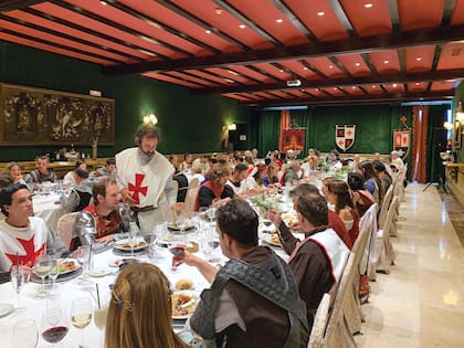 Un banquete medieval, con cordero asado, dulces y quesos dispuestos en una mesa en forma de “U”.