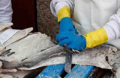 Las manos del pescader emprolijan el bacalao en el mercado de Santiago de Compostela.