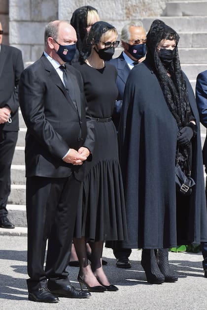 Protegidos por barbijos, con el escudo del principado, Alberto de Mónaco y su mujer Charlene estuvieron muy pendientes de la hija de Elizabeth, Mélanie-Antoinette Costello de Massy (de capa negra). La baronesa también era madre de Jean-Léonard Taubert-Natta de Massy. 