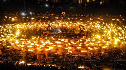 Los miembros vestidos con trajes vikingos llevan antorchas encendidas antes de quemar la galera