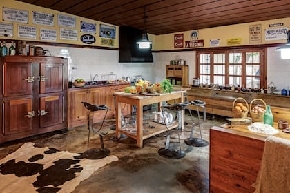 La cocina es el punto neurálgico de la casa y, como en el resto de los ambientes, Dotto le dedicó tiempo a su decoración. Los bancos, adquiridos en Estilo Campo, una tienda de antigüedades “camperas”, están hechos con asientos de tractor y la heladera Berba fue un regalo de un conocido. 