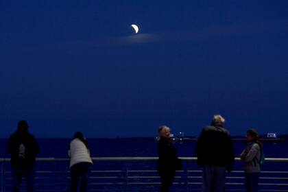 Curiosos miran a la luna en la orilla del río de la Plata en Buenos Aires
