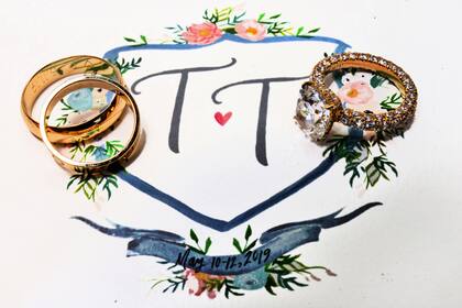 La tarjeta de invitación, pintada a mano, con las iniciales de los novios, Trevor y Tracey, y la fecha de su boda. Sobre ella, las alianzas de oro y el anillo con un gran diamante que el novio le regaló a su prometida.